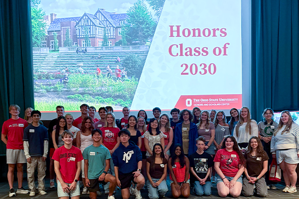 A group of people stand together in front of a presentation screen displaying "Honors Class of 2030"