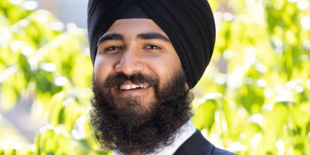 Anitvir S. Taunque wears black turban and and suit with greenery in the background