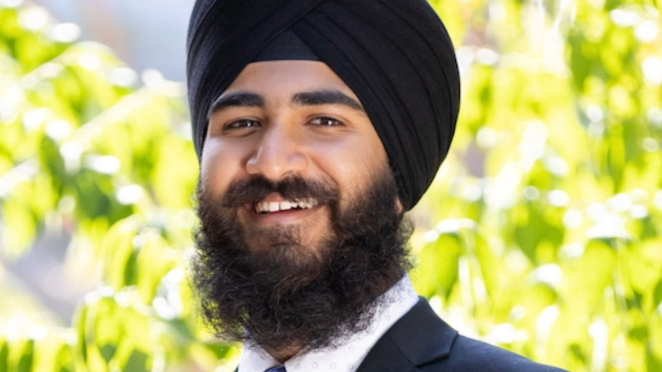 Anitvir S. Taunque wears black turban and and suit with greenery in the background