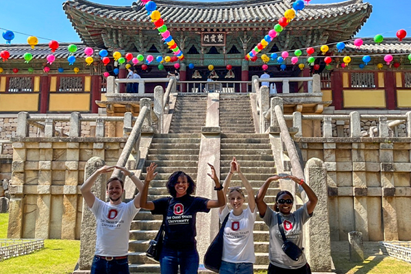 Four people stand in front of the Bulguksa Temple in South Korea, forming the letters "O-H-I-O" with their arms.