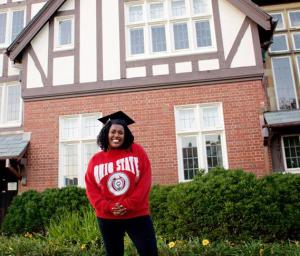 Woman wearing mortarboard in front of Kuhn Honors house.