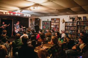 Craig Minnick plays guitar in front of audience at Kafe Kerouac